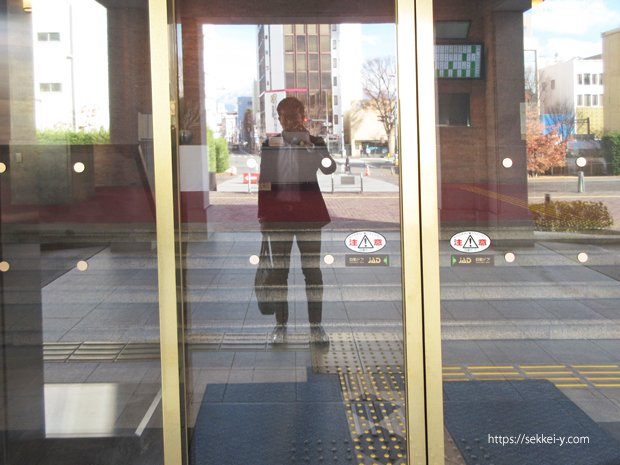 山梨県庁の県議会議事堂　正面入口のガラスに写る吉野聡