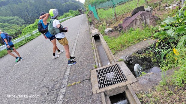 道路沿いの側溝にある配管から水が溢れている