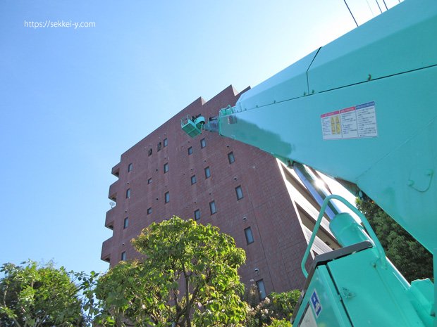 高所作業車を使って高層マンションの換気孔改修工事