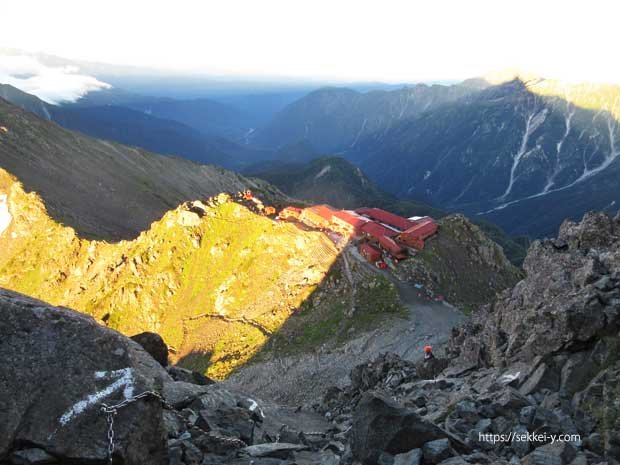 朝日に照らされる槍ヶ岳山荘と槍ヶ岳の影